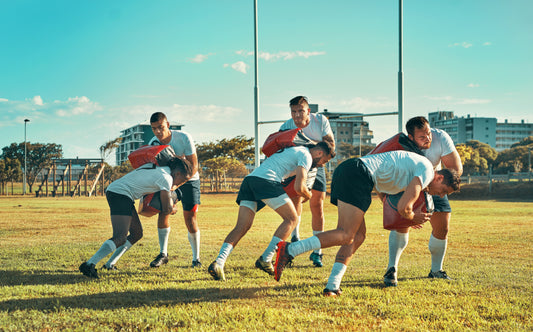 Group of rugby players in action on a field with buildings in the background